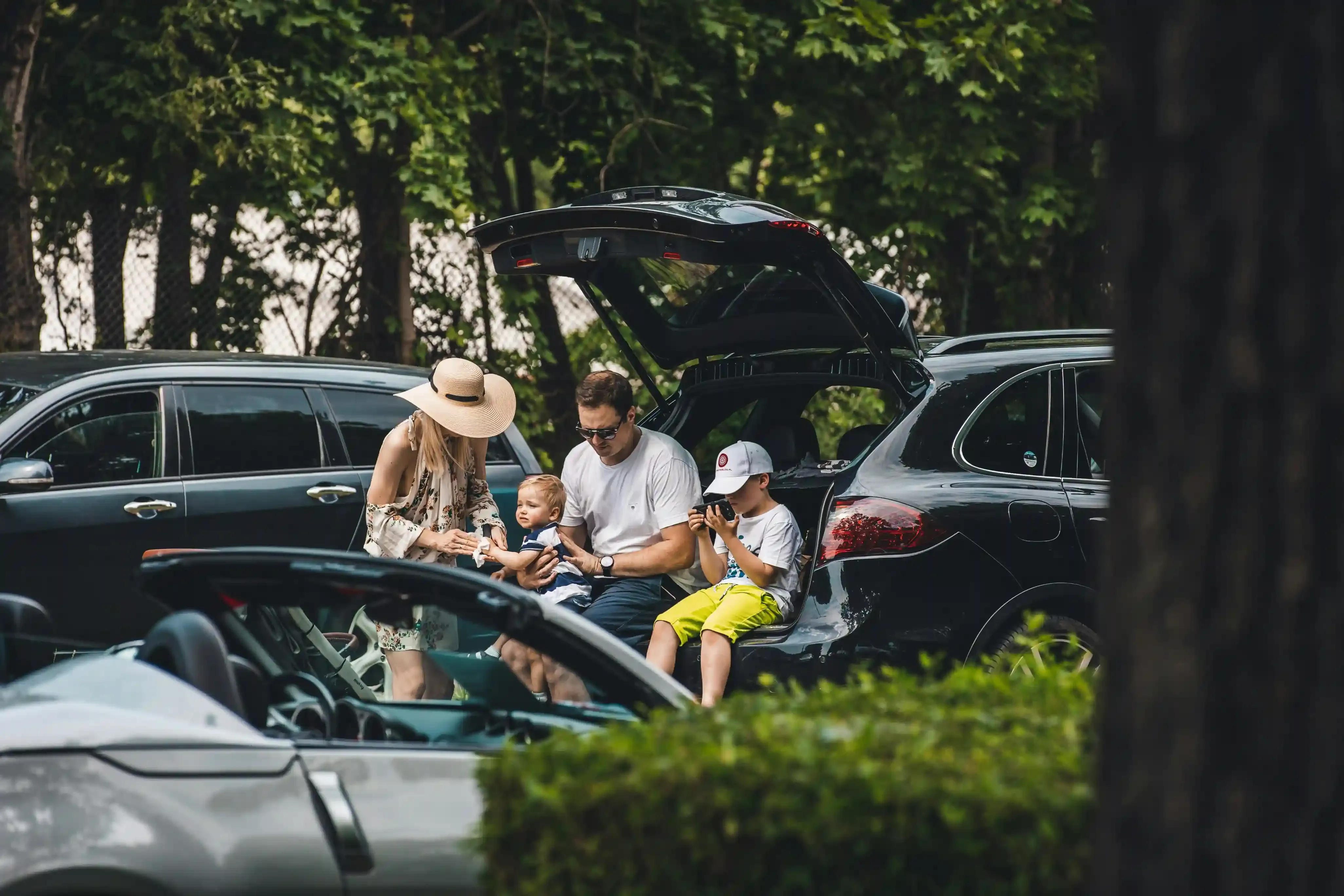Famiglia con due bambini carica i bagagli nel bagagliaio di un SUV elettrico compatto prima di partire per le vacanze