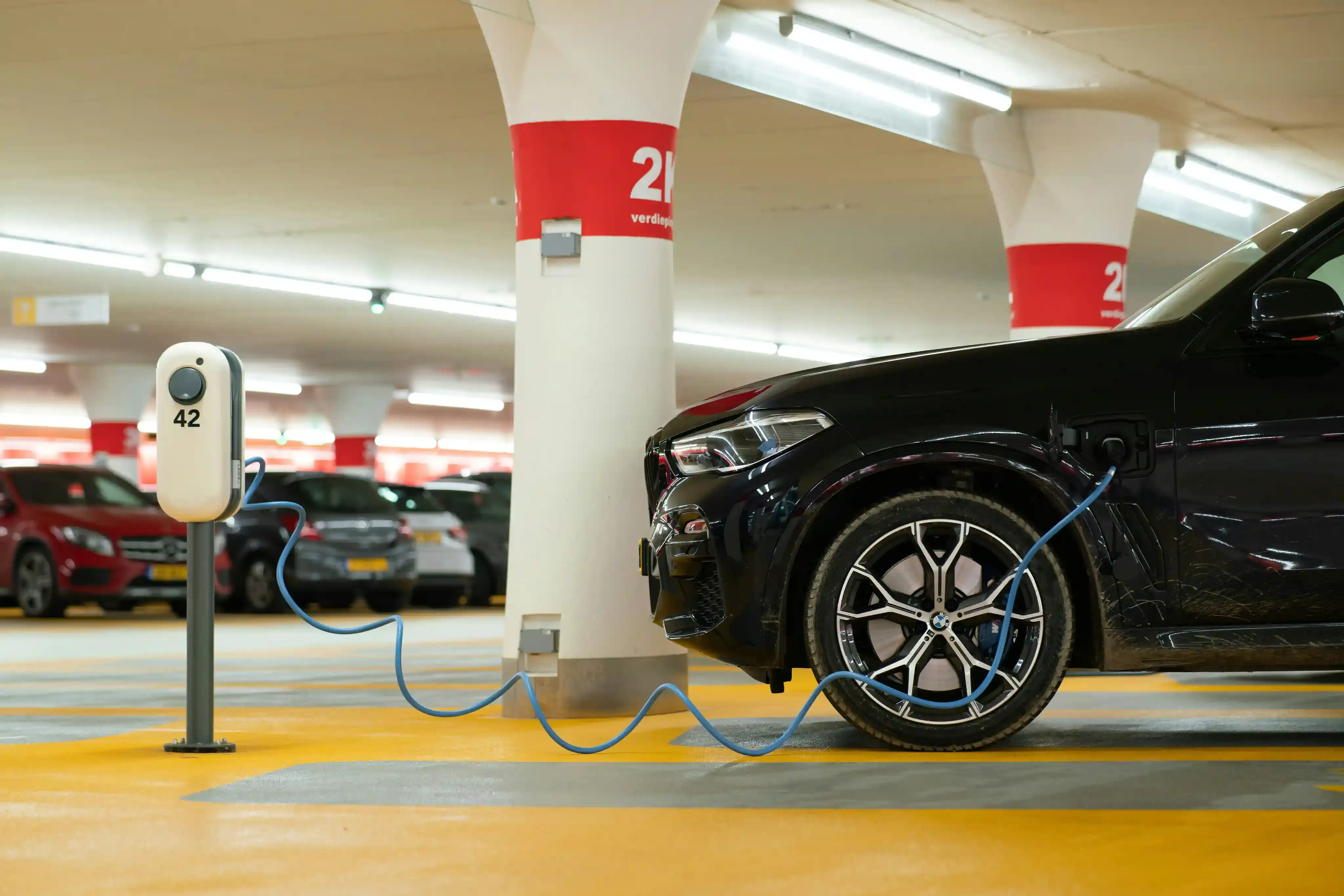 Auto elettrica parcheggiata davanti a un ufficio ACI con documenti del bollo auto sul cruscotto