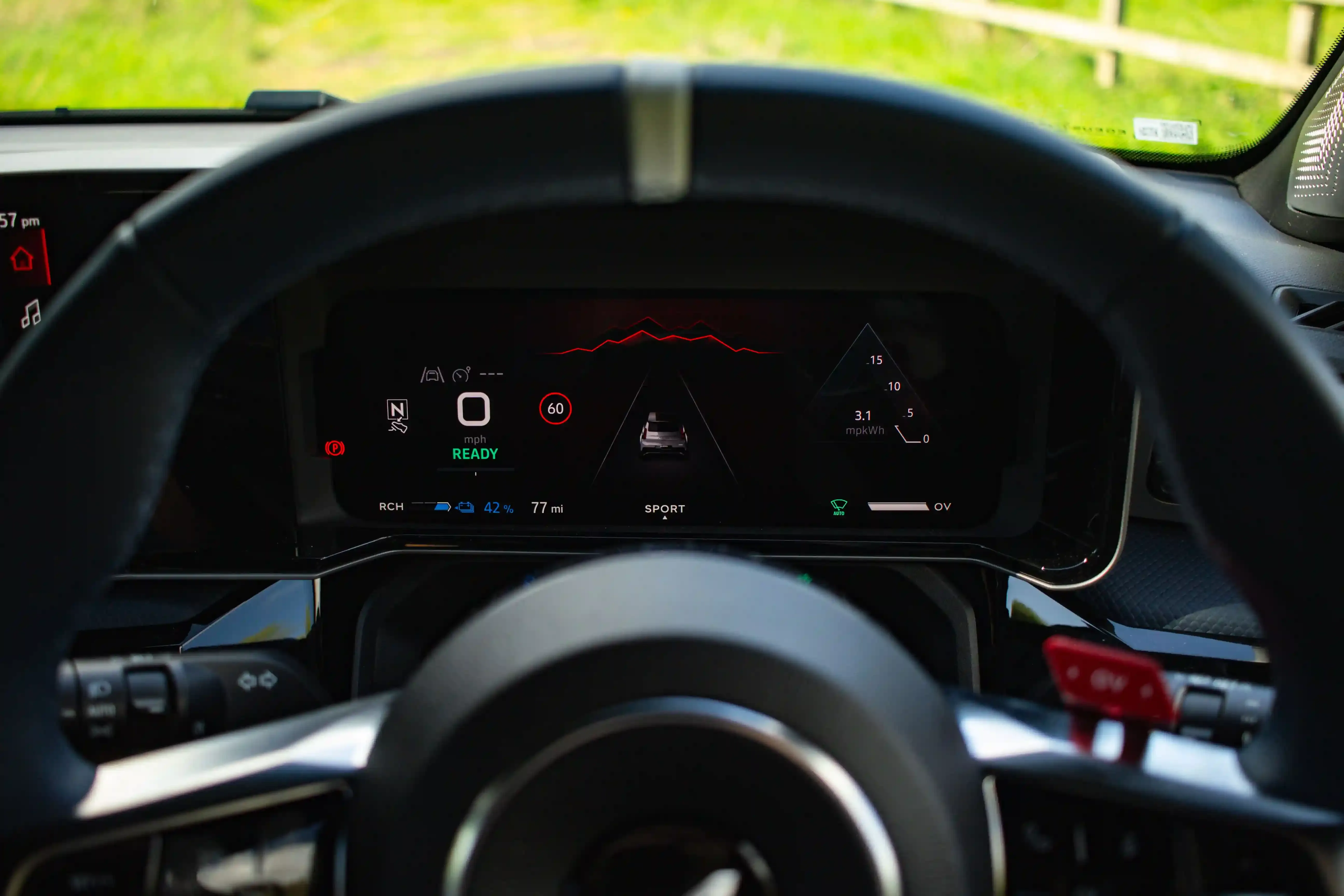 Cruscotto digitale di un'auto elettrica che mostra autonomia residua e consumo medio in kWh durante la guida