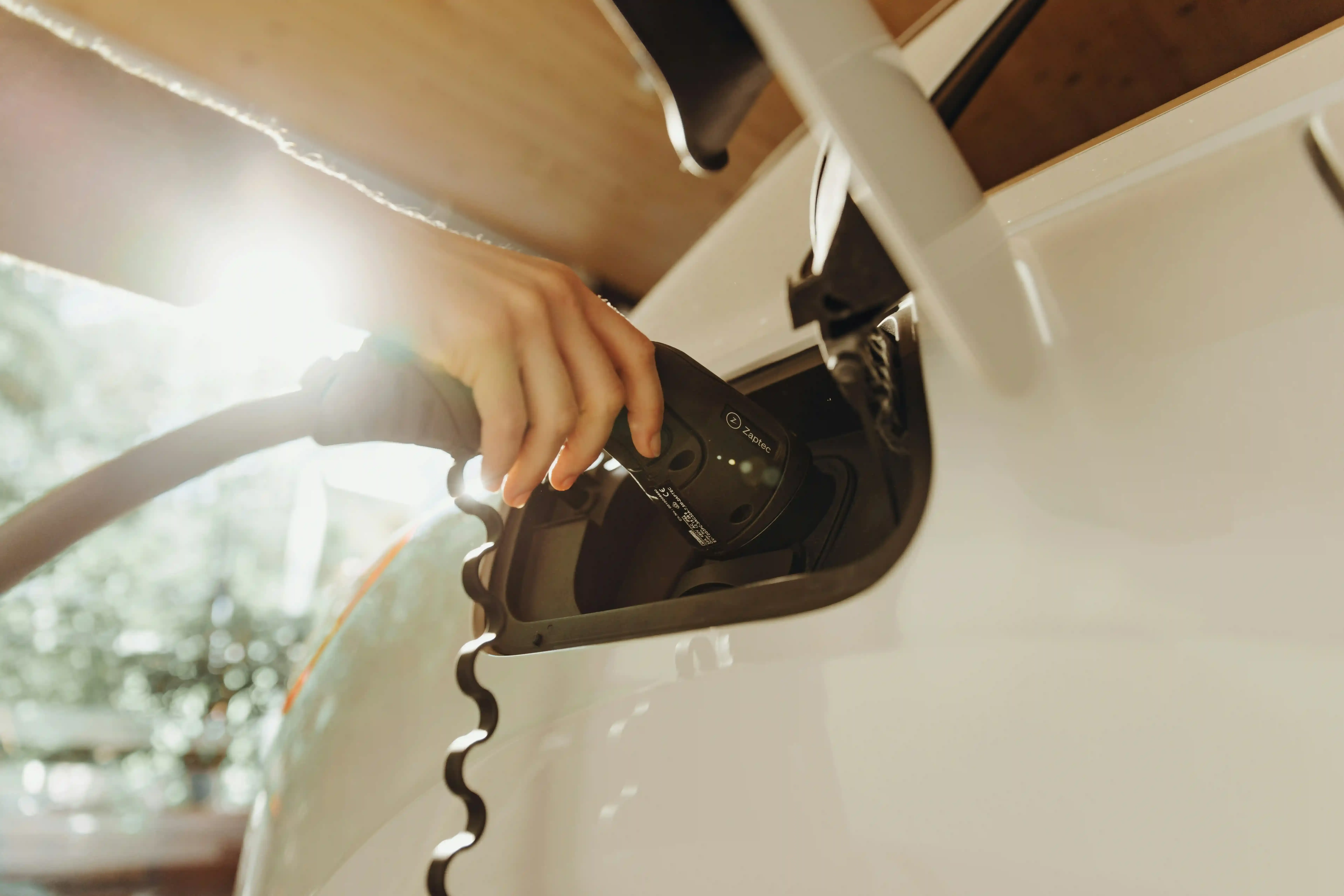 Mano collega il connettore CCS Combo 2 alla presa di ricarica di un'auto elettrica a una colonnina rapida