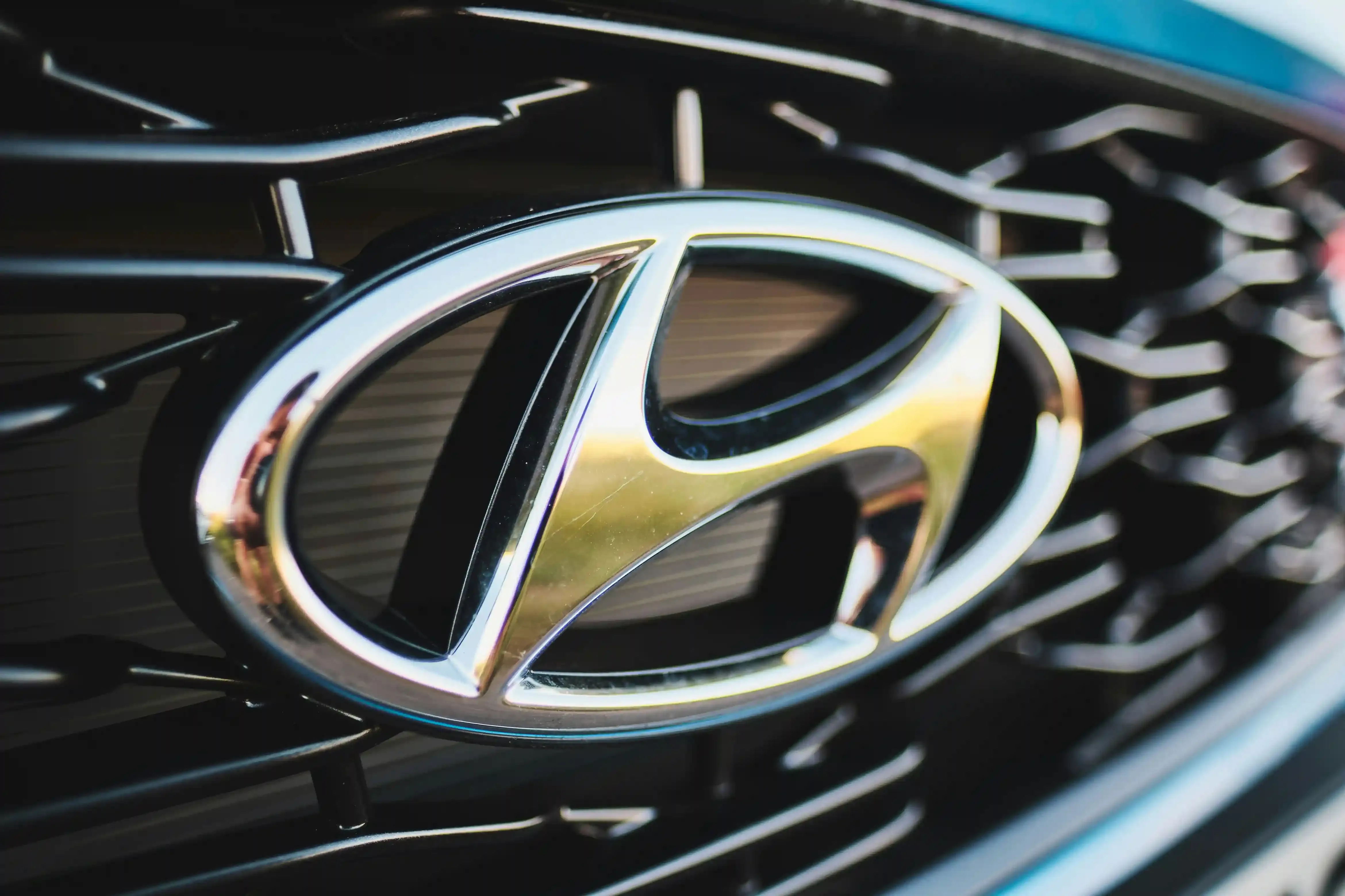 Hyundai Inster verde di tre quarti in un parcheggio urbano, carrozzeria compatta e alta con fari a pixel quadrati