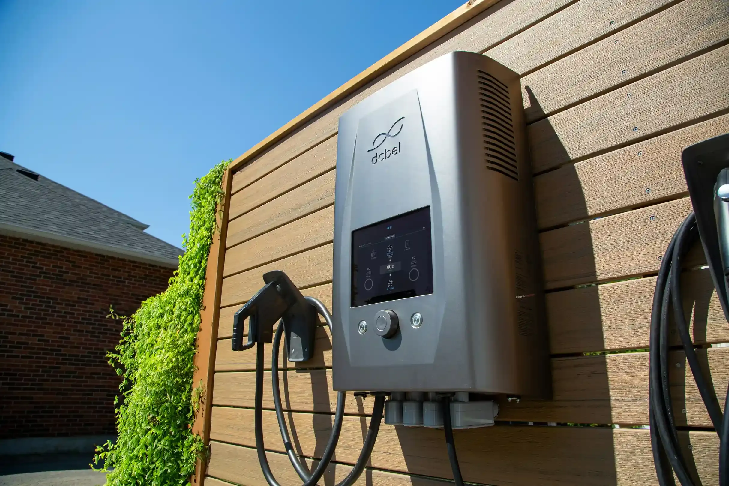 Bolletta della luce accanto a un'auto elettrica in ricarica nel garage di casa con wallbox a parete