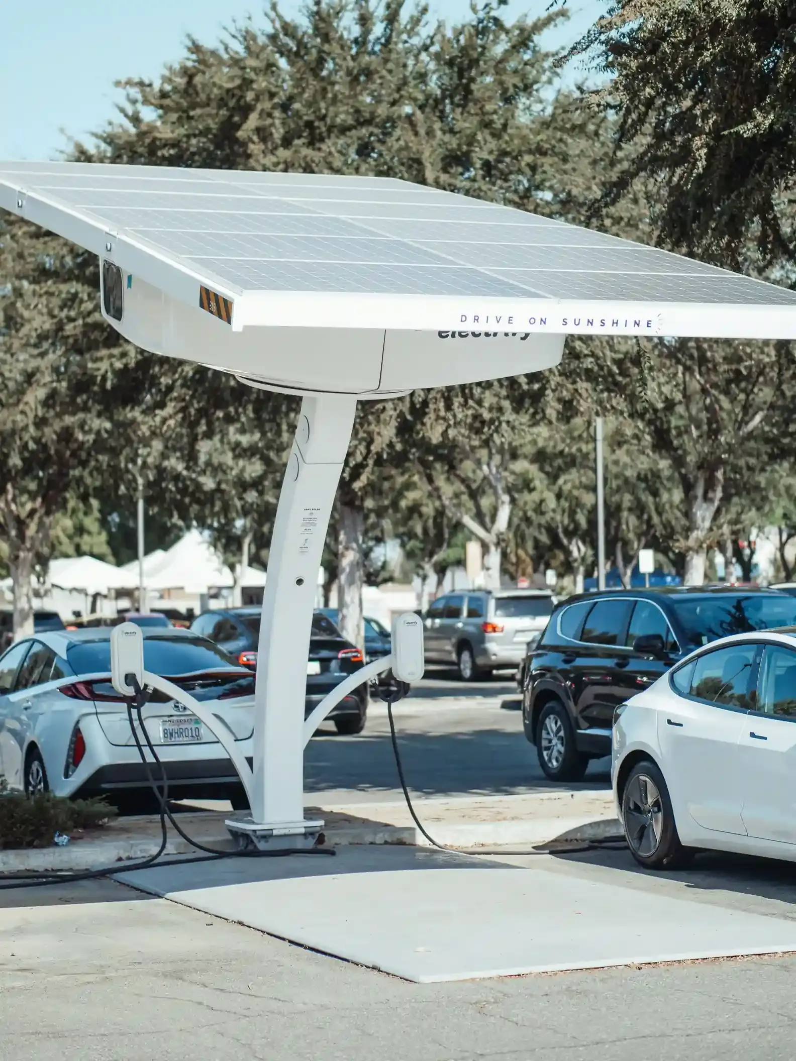 Auto elettrica in carica nel vialetto di casa sotto un tetto con pannelli fotovoltaici al sole