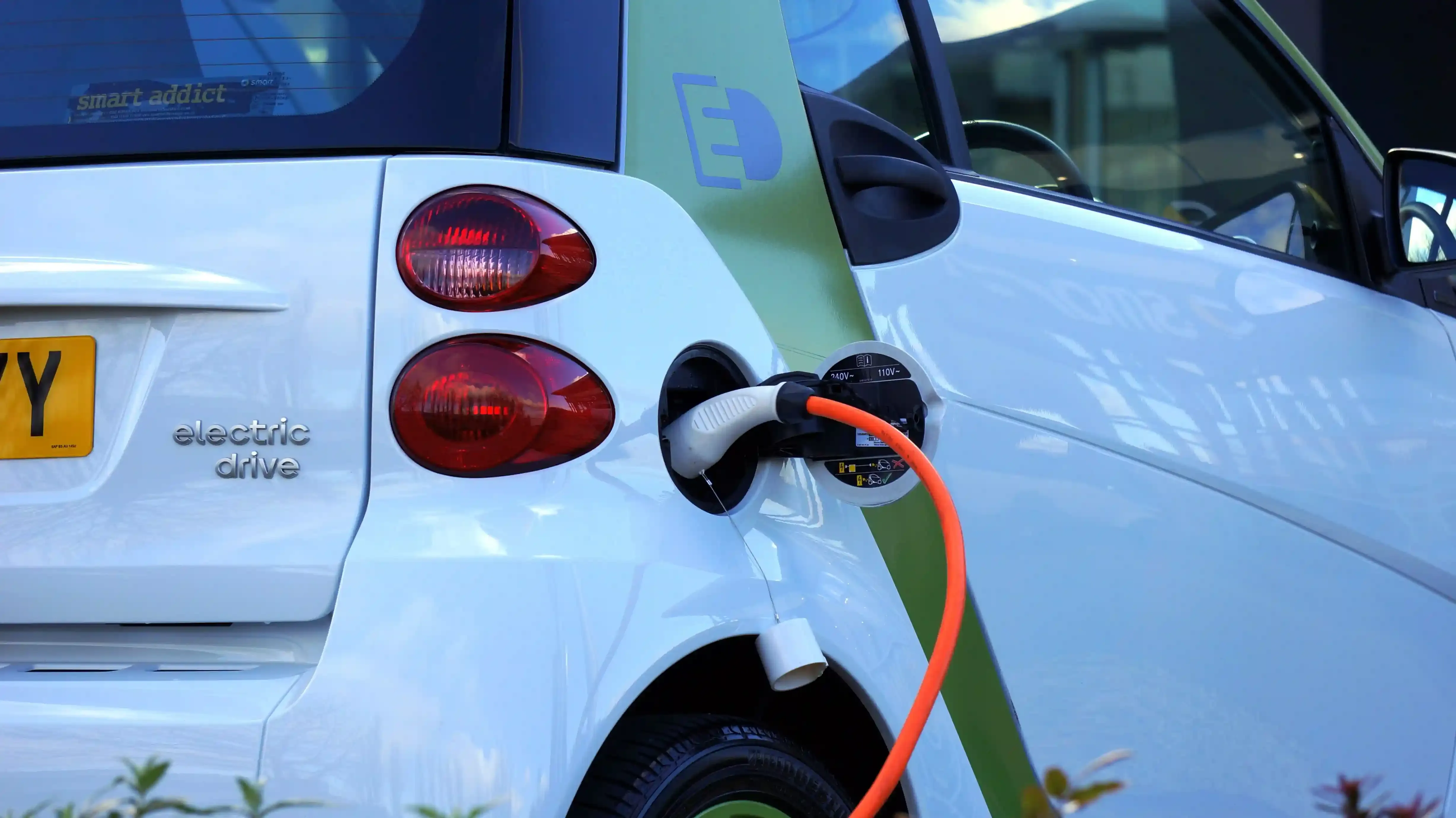 Wallbox installata su un pilastro di un garage condominiale accanto a un'auto elettrica parcheggiata