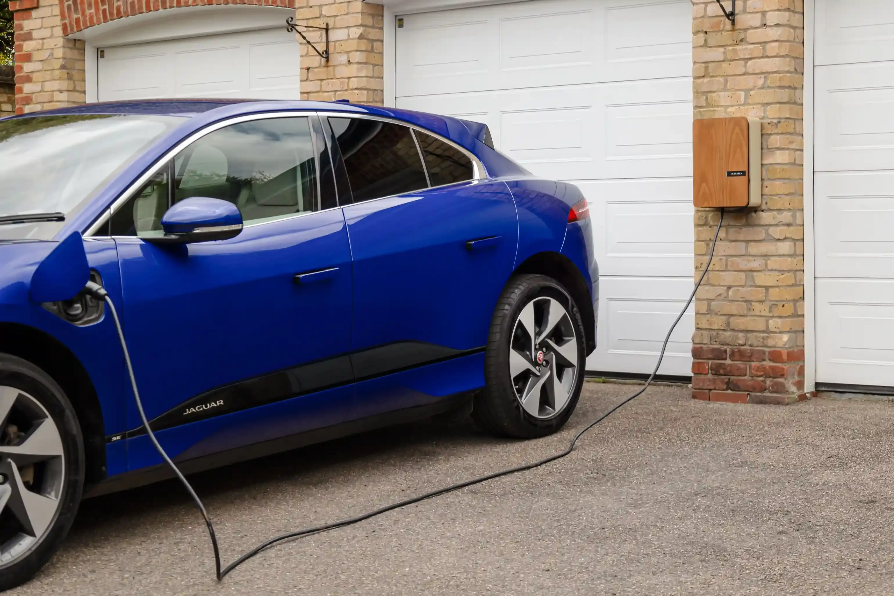 Auto elettrica in ricarica da una wallbox domestica di notte nel vialetto di casa