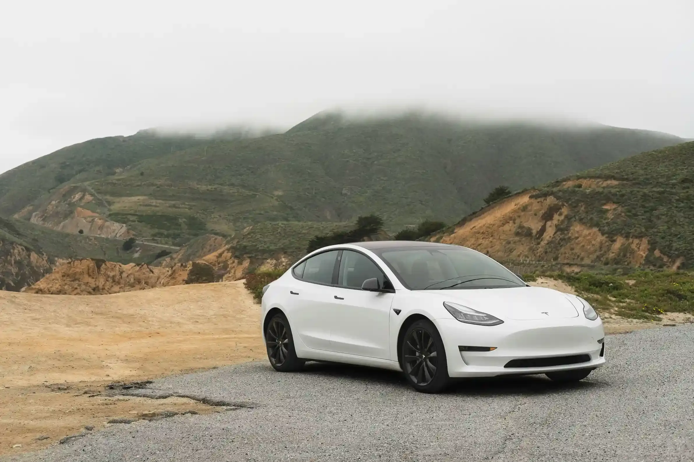 Tesla Model 3 Long Range grigia di profilo su strada extraurbana al tramonto, cerchi da 18 pollici